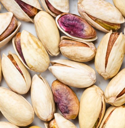 square food background - shelled and ripe pistachio nuts close up